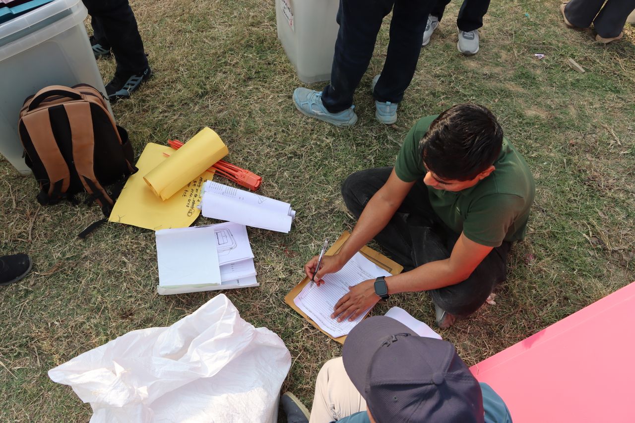 Man sorting electoral papers outdoors in Nepal for upcoming election.